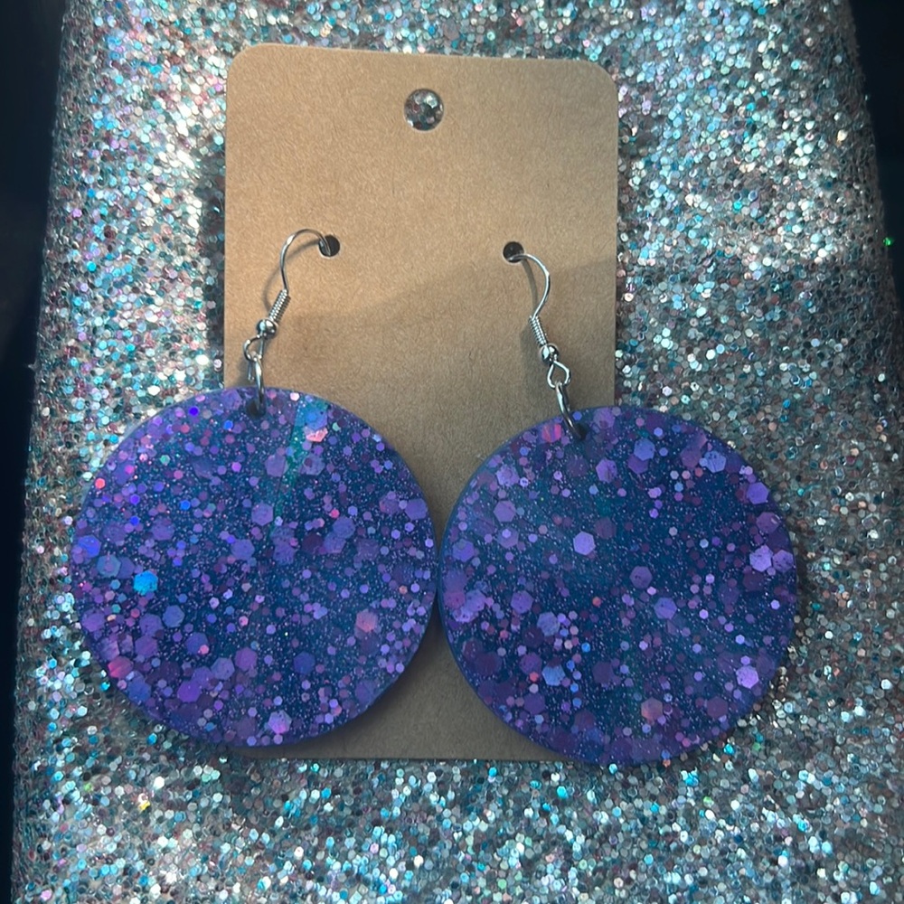 Round earrings blue background with purple glitter.